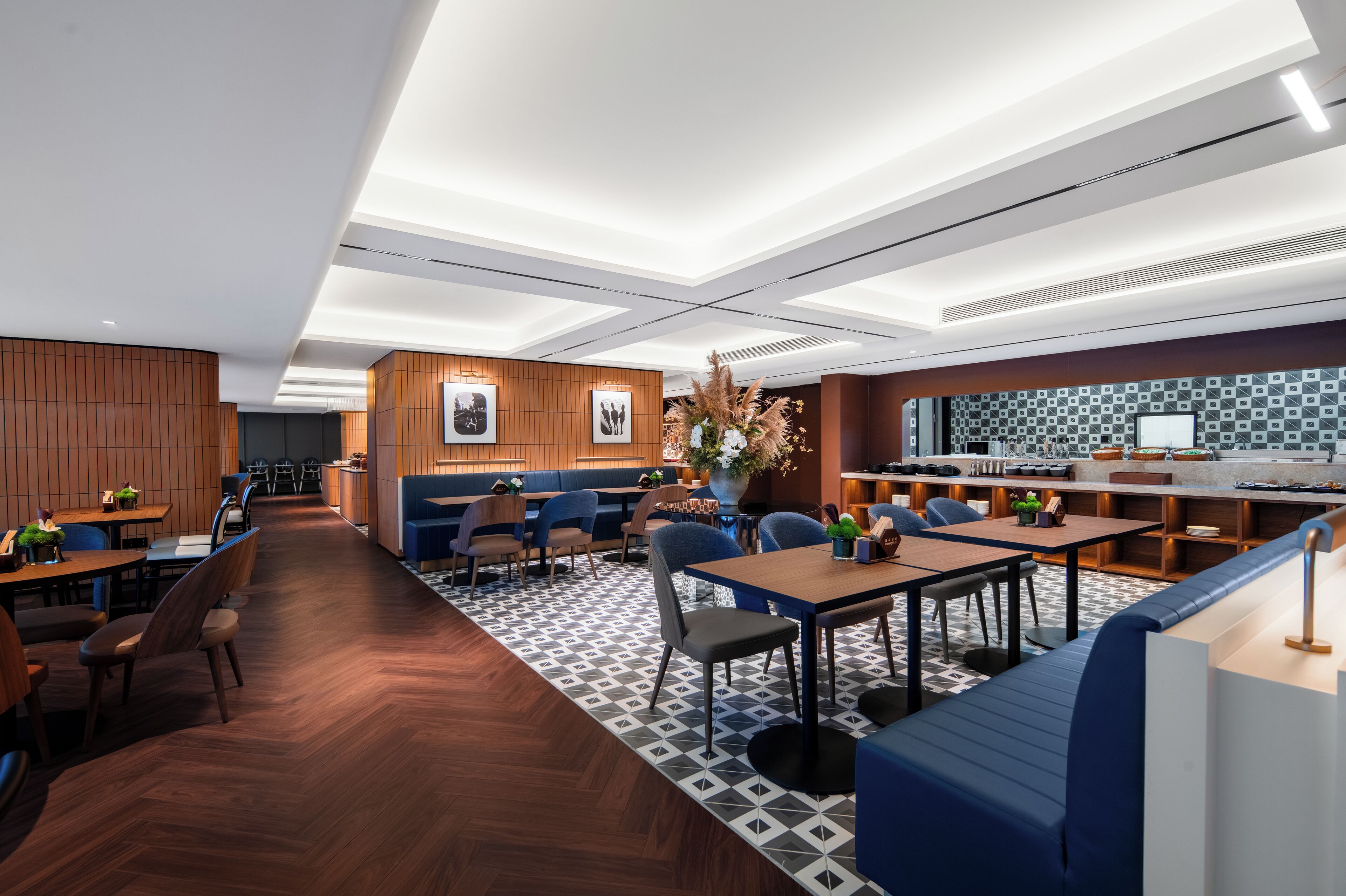 En moderne restaurant med træpaneler, et mønstret gulv og et barområde med flisebeklædt bagpanel.