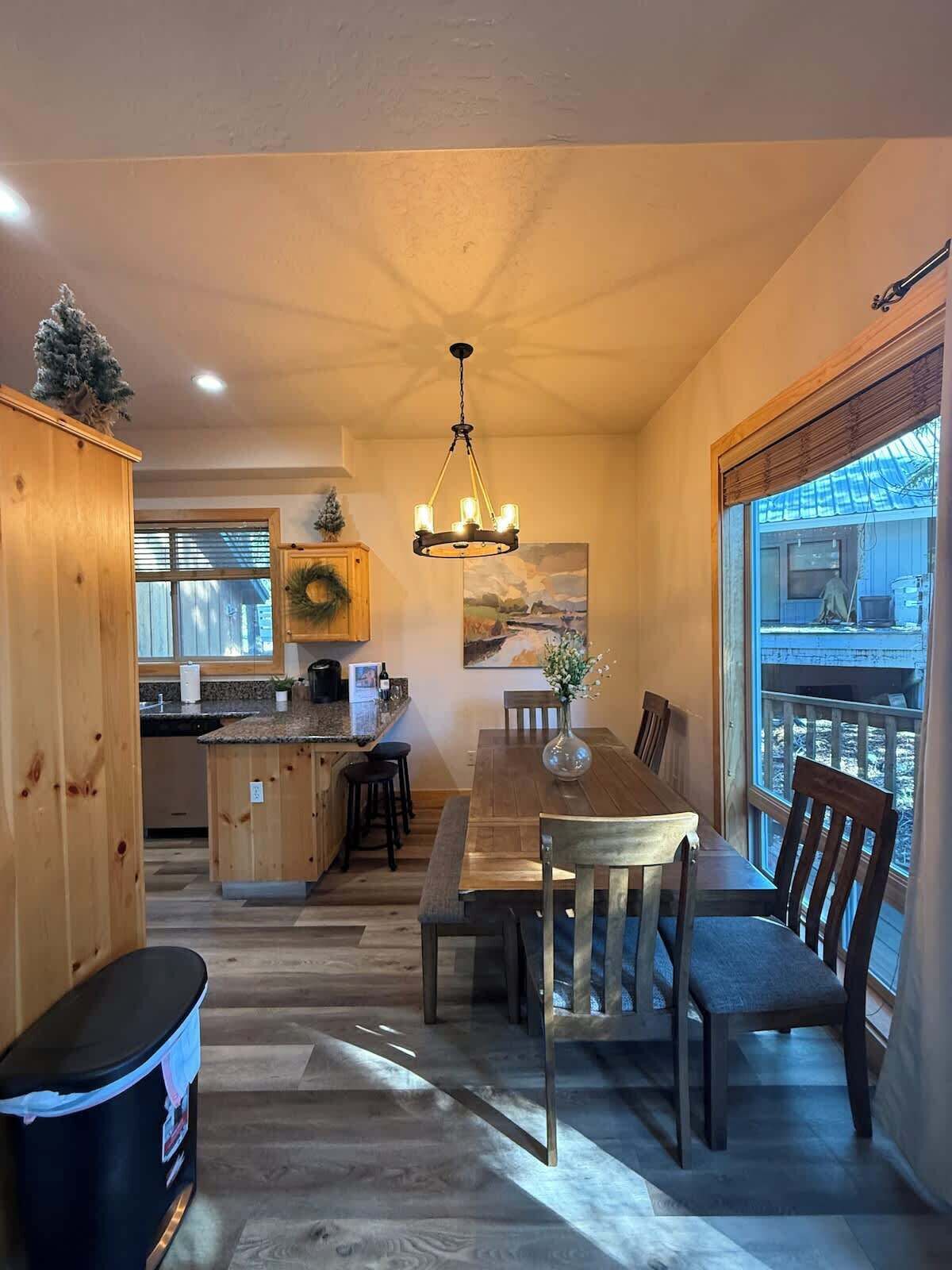 A spacious kitchen with wooden cabinets, a dining area with a table and chairs, and a large window with a view.