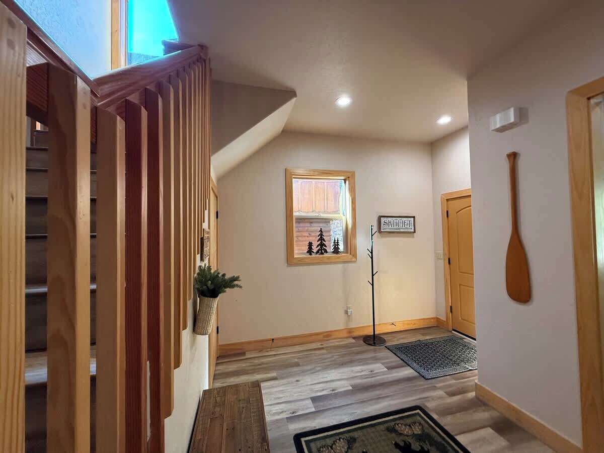 A wooden staircase leading to a landing with a small window, a door, and a wall-mounted wooden paddle.