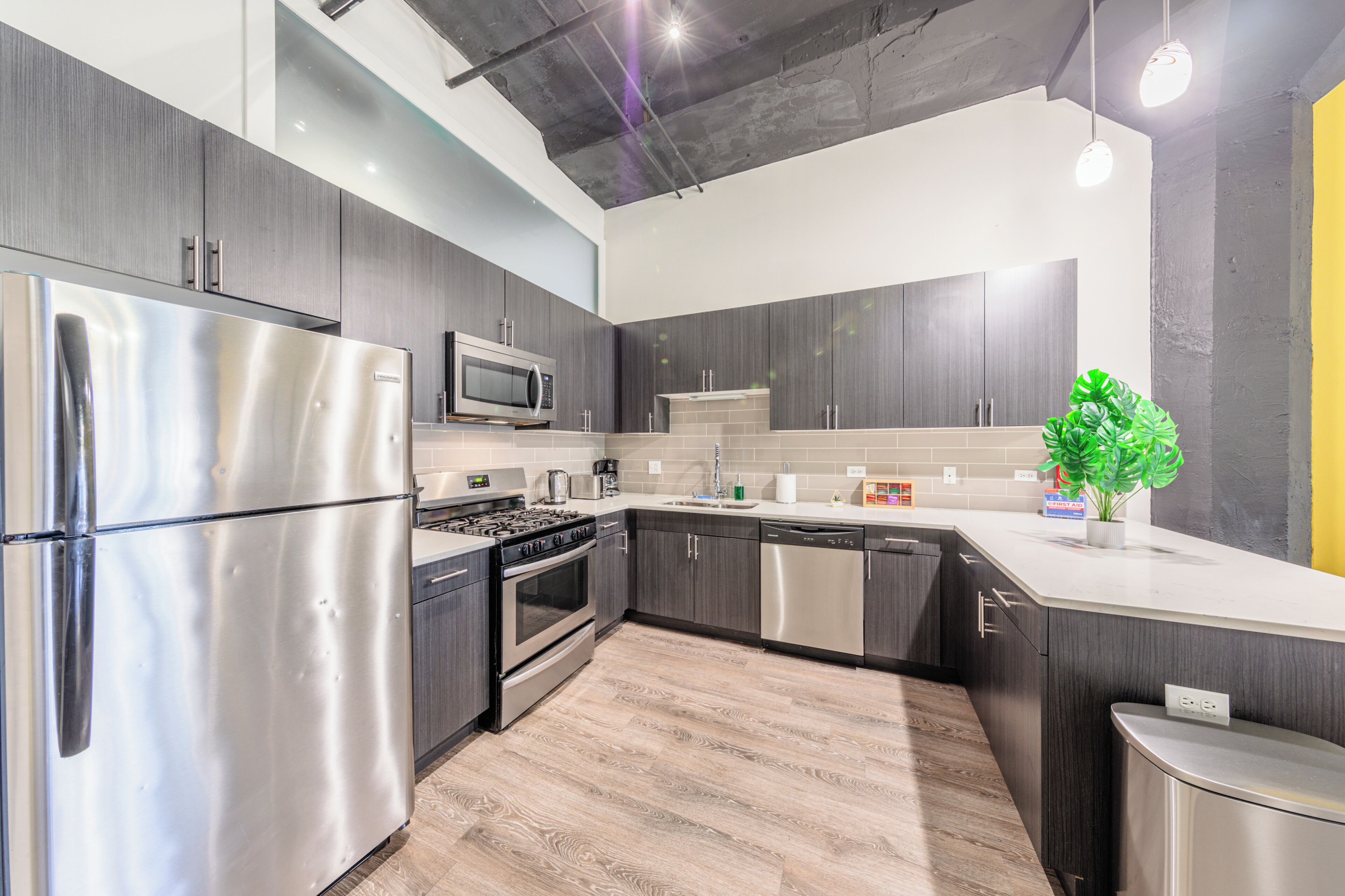 A modern kitchen with stainless steel appliances, dark wood cabinets, and a light-colored countertop.