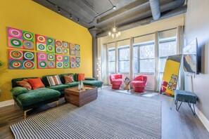 A modern living room with a green sofa, red chairs, a coffee table, and colorful wall art. - Modern 3BR BA Downtown Chicago Getaway Near McCormick (Chicago)