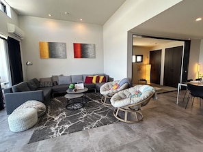 A modern living room with a sofa, two bean bag chairs, a coffee table, and artwork on the wall. - Luxuary Villa Maeda I (Kunigami-gun)