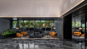 A modern lobby with a marble floor, black and orange seating, and large windows offering a view of greenery. - IntercityHotel Gaungzhou Financial City (Guangzhou)