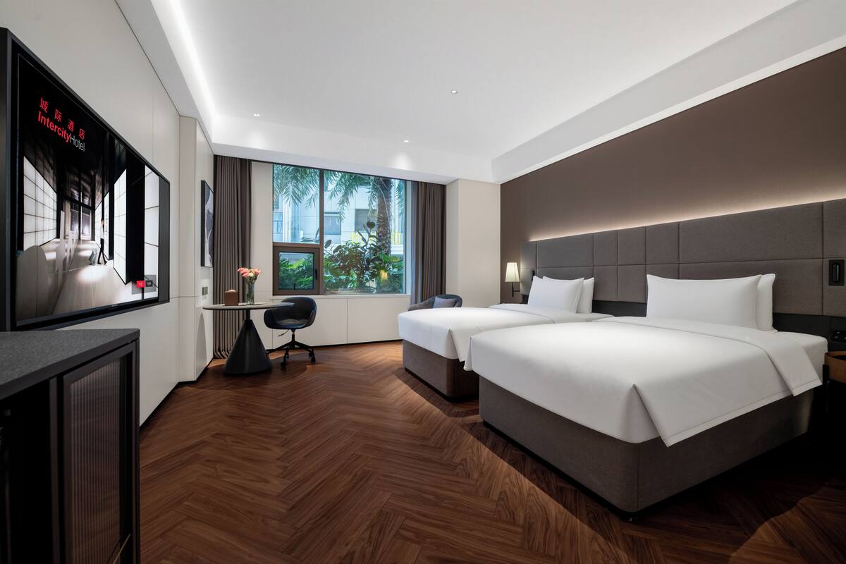 Ein modernes Hotelzimmer mit einem großen Bett, einem Schreibtisch, einem Sessel und einem Fernseher.