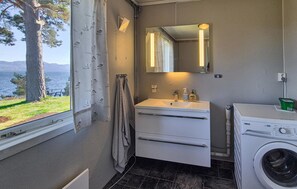 A bathroom with a window, a sink, a mirror, a towel rack, and a washing machine. - 4 bedroom awesome home in Fusa (Fusa)