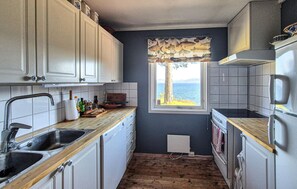 A compact kitchen with a view of the sea, a window with a curtain, and a wooden floor. - 4 bedroom awesome home in Fusa (Fusa)