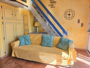 Ein Zimmer mit einer Couch, einer Treppe und einer Wanduhr.