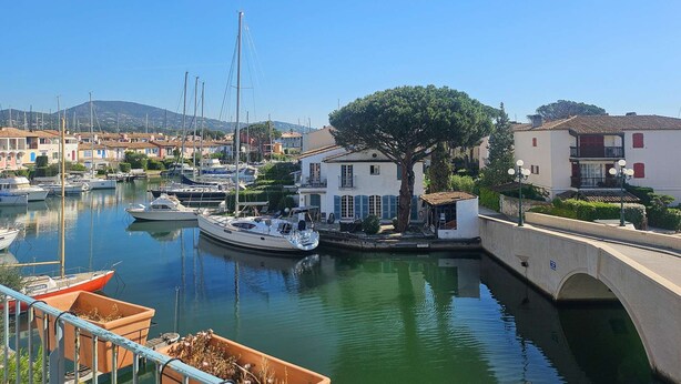 A marina with boats, a bridge, and buildings with balconies. - A pleasant, air-conditioned studio with Wi-Fi in the heart of Port Grimaud Sud, (PORT GRIMAUD)
