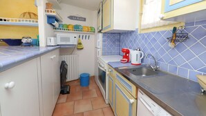A compact kitchen with a microwave, toaster, and coffee maker. There is a blue trash bin and a dish rack with plates. - A pleasant, air-conditioned studio with Wi-Fi in the heart of Port Grimaud Sud, (PORT GRIMAUD)