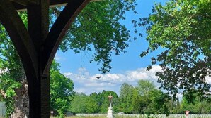 Un vignoble avec des rangées de vignes, une statue blanche et un ciel d’un bleu limpide.