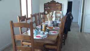 A dining area with a wooden table, chairs, and a bookshelf in the background.
