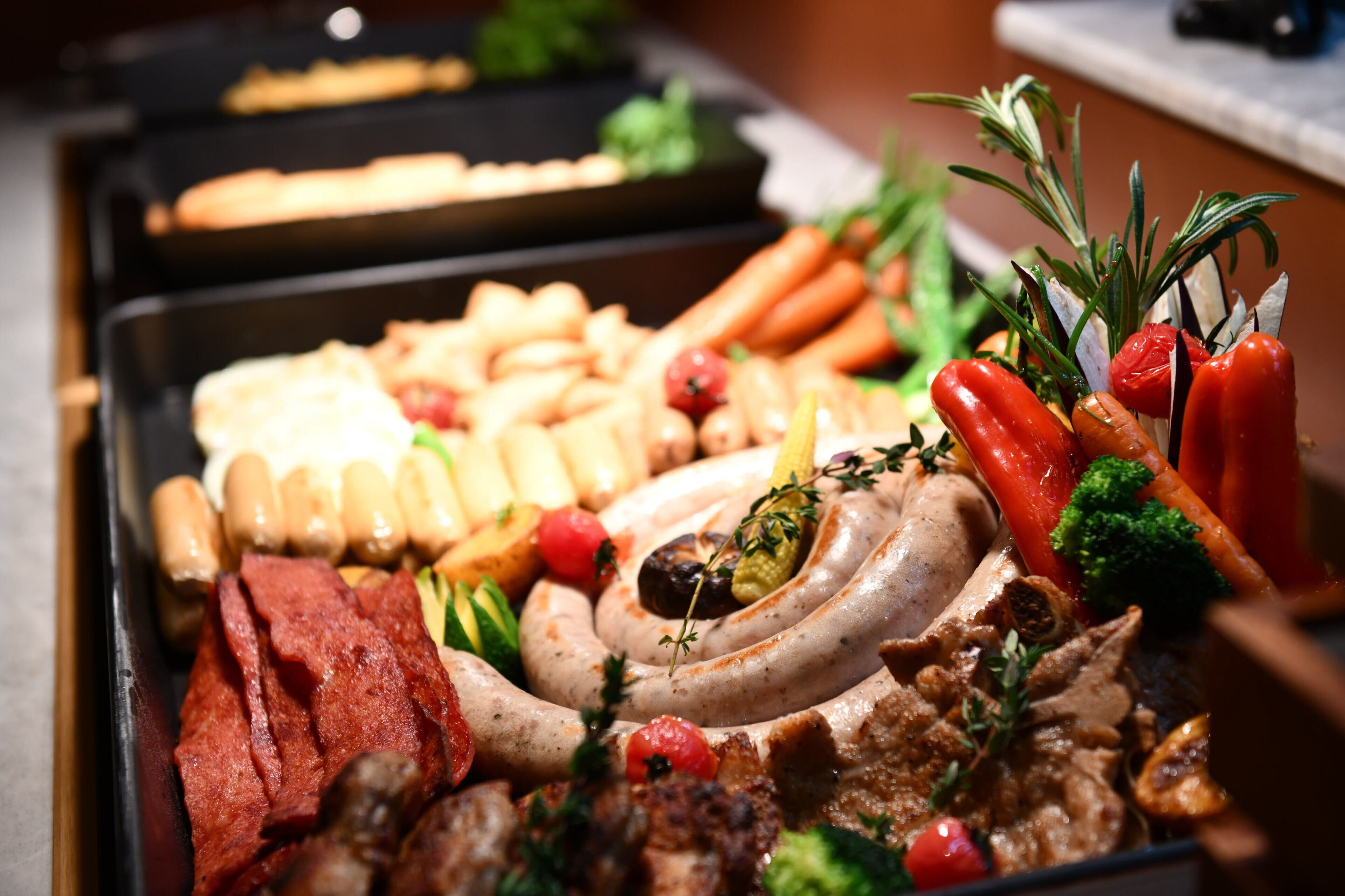 Un bufé con diversos tipos de carne, verduras y pan.