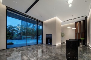 Um hall moderno com grandes portas de vidro, lareira e balcão de recepção.
