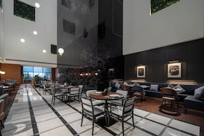 Un intérieur moderne avec un sol à carreaux, des tables rondes et des coins salons bleus.