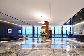 Un hall d’entrée spacieux, doté d’un sol en marbre, de grandes fenêtres et d’un comptoir de réception.