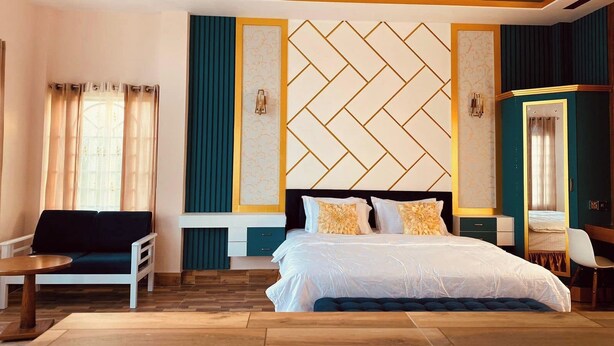 A bedroom with a bed, a seating area, a dresser, and a mirror. - Aronnonibash Eco Resort (Kamalganj)