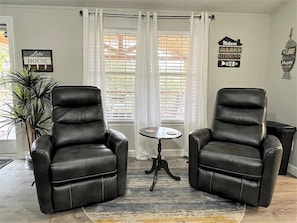 Two black leather chairs, a small round table, and a potted plant in a room with white curtains and a sign that reads 'Welcome to the Lake House.' - NEW! Lakefront Home with Private Dock & Steps to Water (Jacksboro)