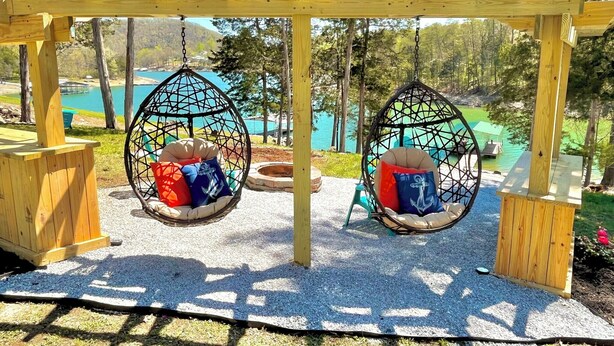 A wooden pergola with two hanging swing seats.