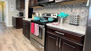 A modern kitchen with dark wooden cabinets, stainless steel appliances, and a tiled backsplash.