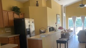 Una cocina moderna con armarios de madera, una isla central, un refrigerador y un comedor con sofá y sillas.