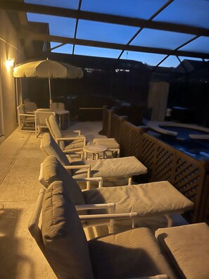 An outdoor seating area with wicker chairs and a table, a pool, and a covered section with a glass ceiling. - Cozy Family Stay Near Orlando & Disney (Clermont)
