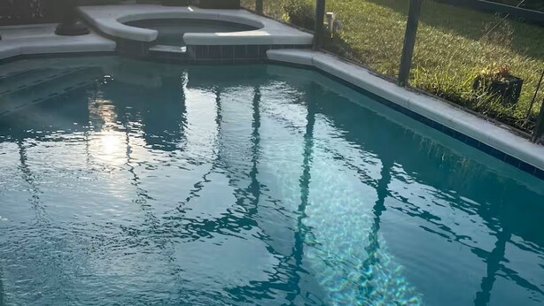 Una piscina cristalina con borde de azulejos y zona de jacuzzi.