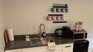 Une cuisine compacte équipée d’un évier, d’un espace pour préparer le café et d’un four à micro-ondes.