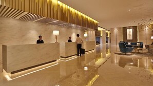 Eine moderne Hotelhalle mit Marmor-Rezeptionstheken, einem polierten Boden und zeitgenössischen Möbeln.