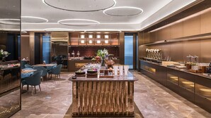Eine moderne Hotelhalle mit einer zentralen Bar, Sitzgelegenheiten und einer Rezeption.