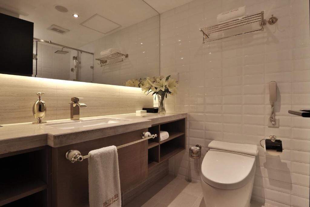 A modern bathroom with a large mirror, a sink, a toilet, and a shower.