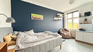 A bedroom with a bed, bedside lamp, and a window with a view of buildings. - City Apartment in Copenhagen with 3 bedrooms sleeps 4 (Copenhagen)