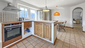 A kitchen with a built-in oven, a wooden cabinet, a window, and a pendant light. - Open Sky Retreat Panoramic Alpine Views 6 Sleeps (Chelin)