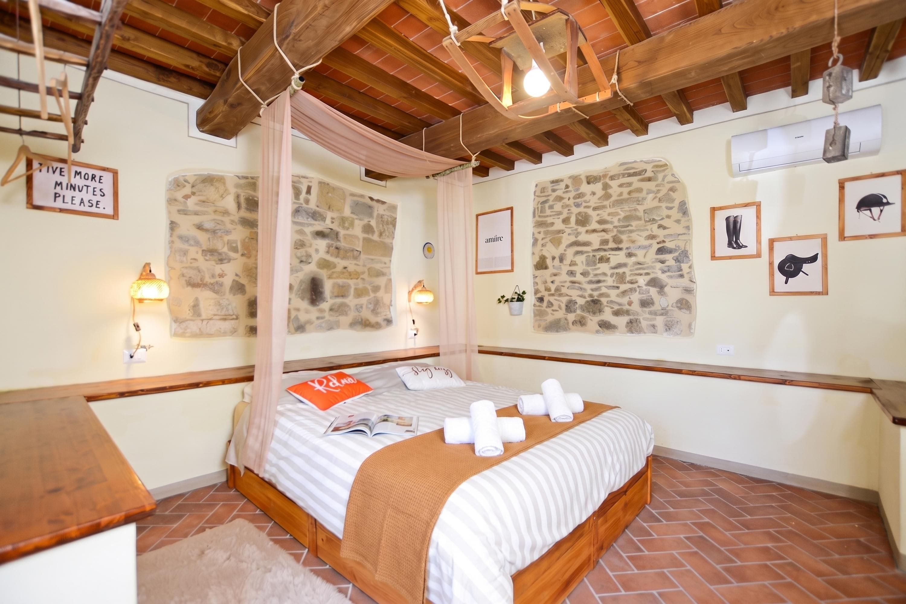 Una camera da letto con una parete in pietra, un letto con copripiumino a righe e un cartello appeso al muro.