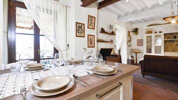 Un comedor con una mesa de madera dispuesta para cuatro personas, rodeado de paredes blancas con impresiones botánicas enmarcadas.