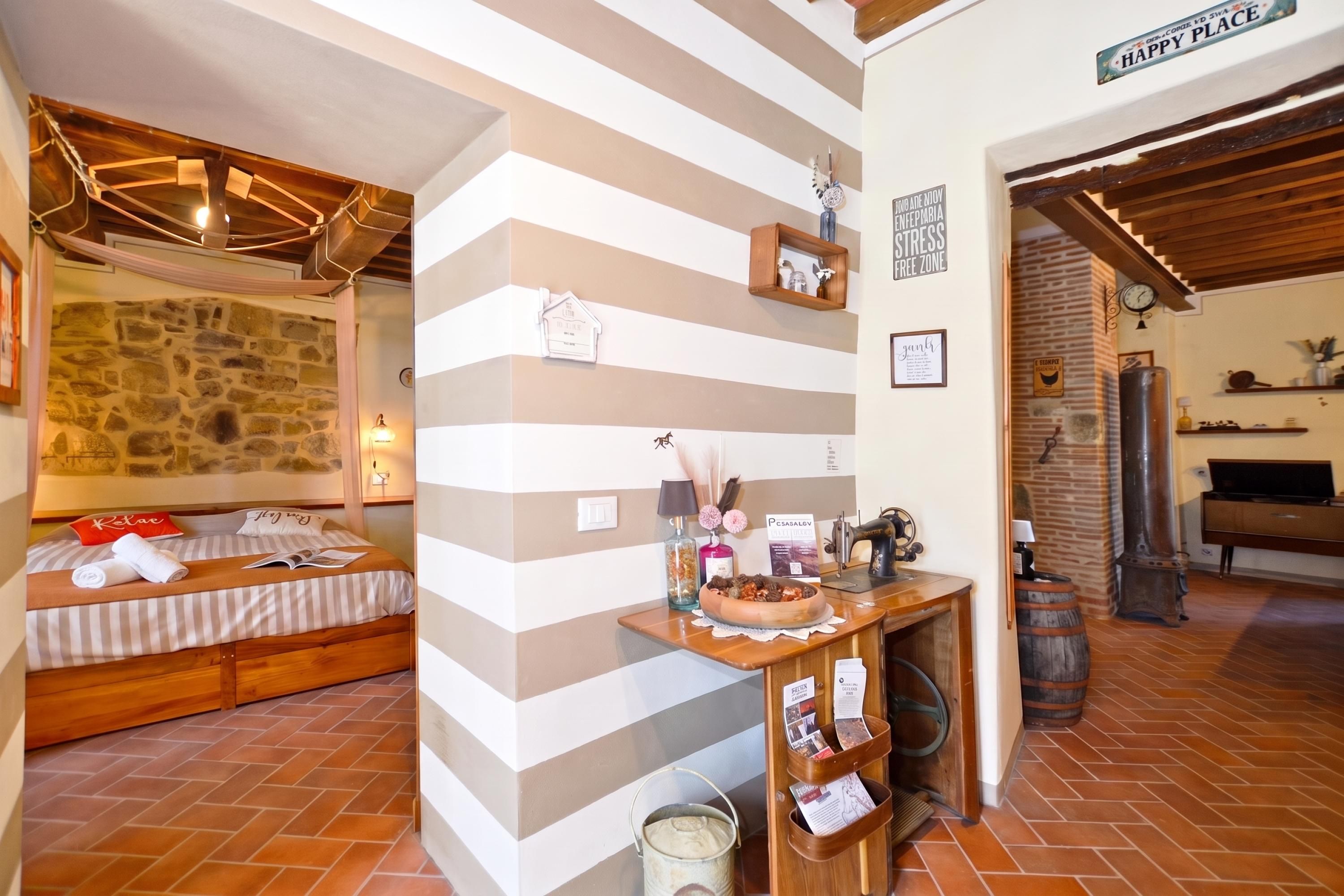 Une pièce confortable avec un lit, un bureau en bois et un mur en pierre.