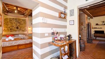 Une pièce confortable avec un lit, un bureau en bois et un mur en pierre.