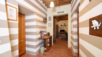 Un pasillo con paredes a rayas, una puerta de madera, una estantería con diversos objetos y un letrero que dice 'HAPPY PLACE'.