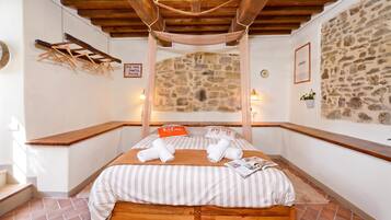 Un dormitorio acogedor con pared de piedra, techo de madera y cama con ropa de cama a rayas.