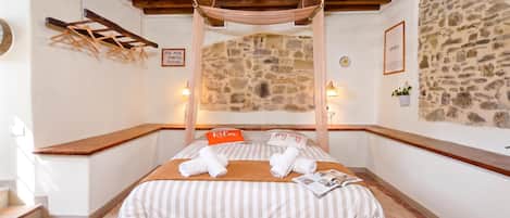 Un dormitorio acogedor con pared de piedra, techo de madera y cama con ropa de cama a rayas.