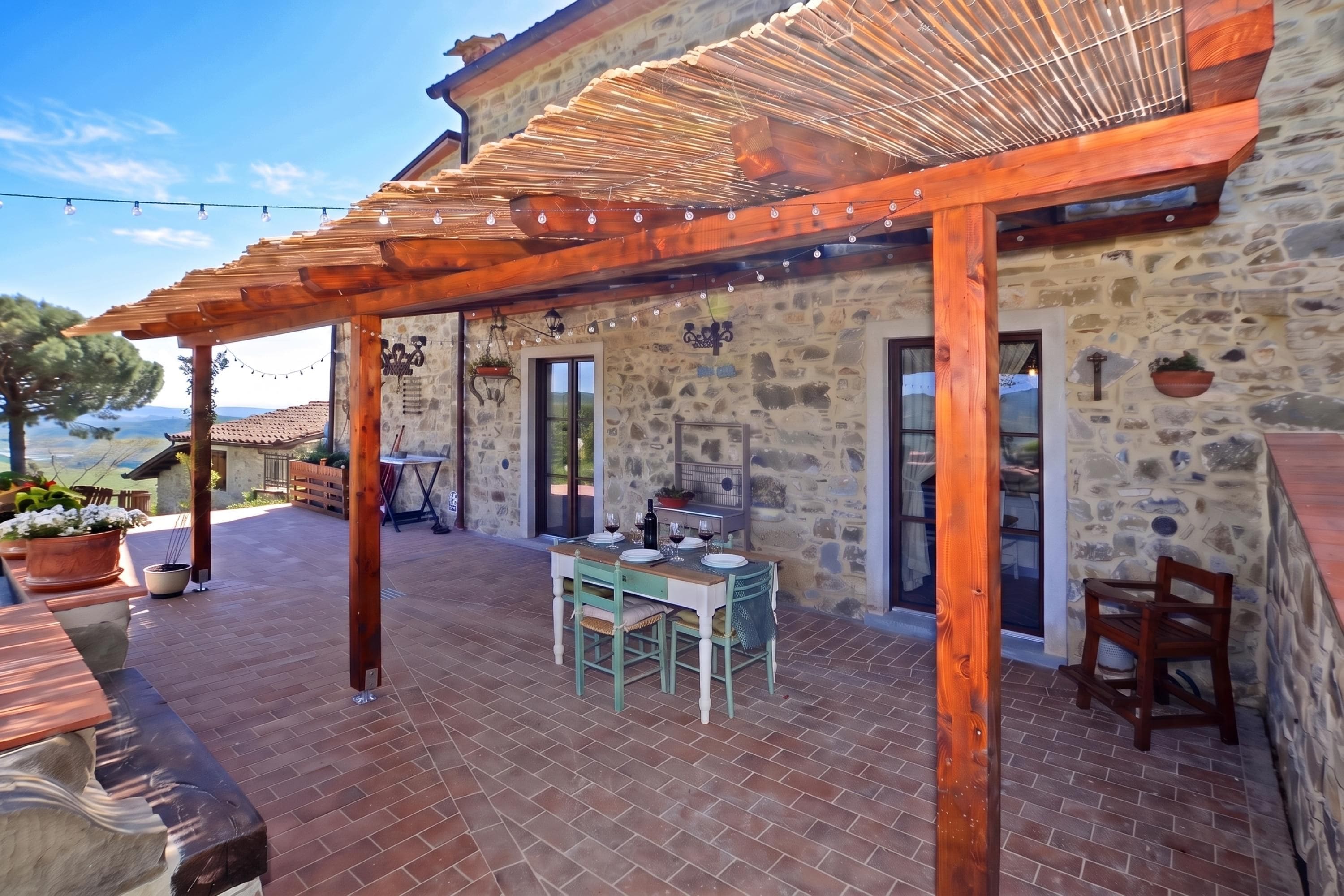 Un edificio de piedra con un patio cubierto, asientos exteriores y vistas del paisaje.