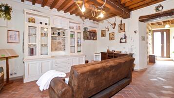 Un interior rústico con un banco de madera, pared de piedra y diversos objetos decorativos.