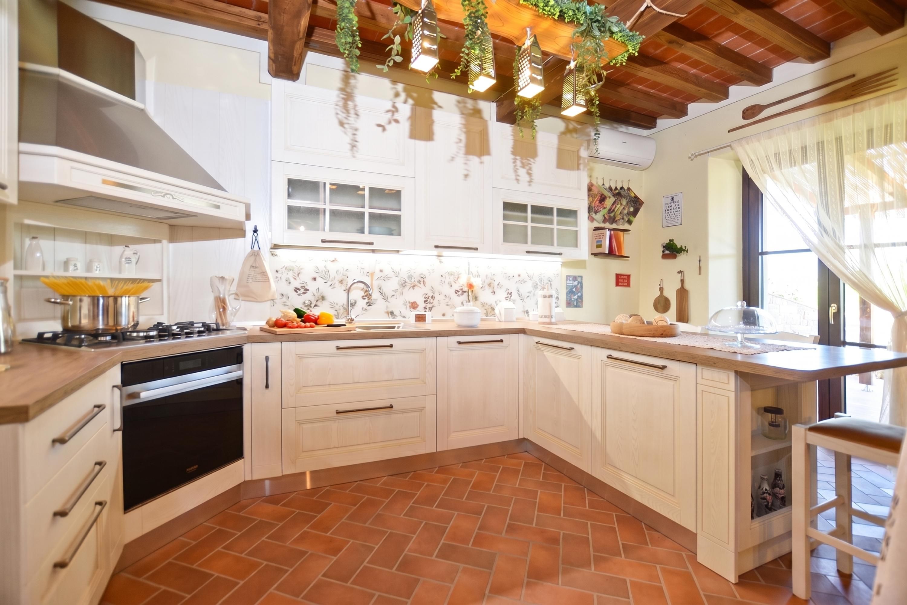 Cocina con armarios blancos, estufa y piso de baldosas.