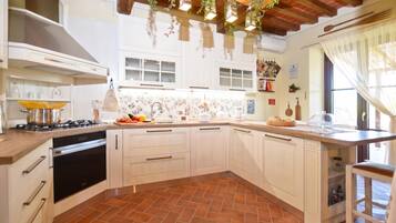 Cocina con armarios blancos, estufa y piso de baldosas.