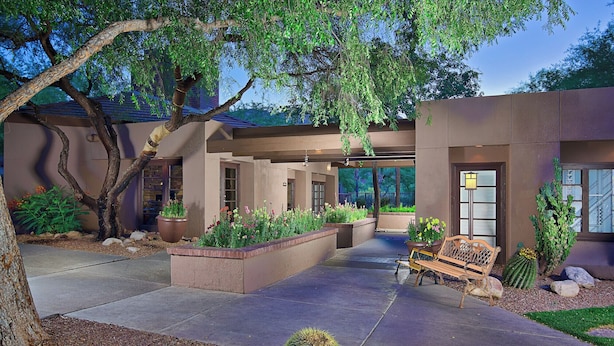 Un patio moderno al aire libre con un banco, macetas y un cactus.