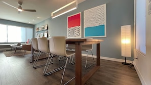 Un comedor moderno con una mesa de madera, sillas metálicas y obras de arte en las paredes.