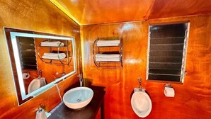 Een badkamer met houten inrichting, een wastafel, een spiegel, twee handdoekhouders en een raam.
