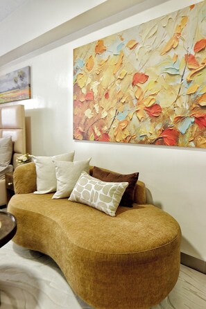 A modern living room with a curved sofa, a large abstract painting, and a small round table. - Stylish duplex studio with balcony, fast Wi-Fi, cozy luxury & city vibes. (Nairobi)