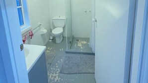Et badeværelse med toilet, vask og bruseområde.