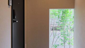A hallway with a door, a security camera, and a view of a tree through a window.