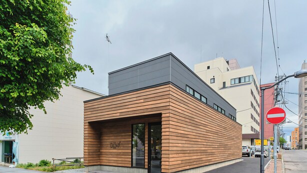 A modern building with a flat roof, large windows, and a wooden facade.